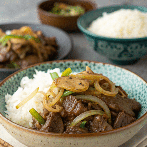 Bœuf sauté aux oignons dans un bol avec riz blanc et oignons fondants, plat asiatique maison